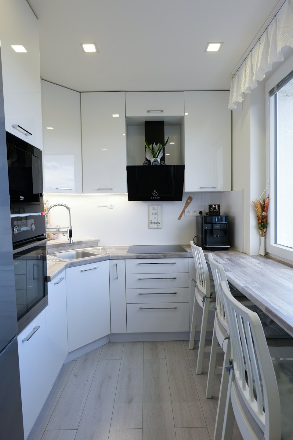 Cucina moderna e compatta con mobili bianchi e piano di lavoro in legno.